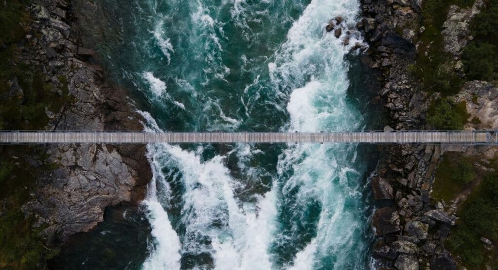 Bro över flod i Jokkmokk, Sverige – symbol för samarbete, strategi och nya möjligheter i samklang med naturen.